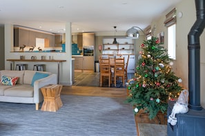 A modern living room with a sofa, coffee table, and a Christmas tree. - Sleeps 8, 4 Bedrooms, Dogs Welcome, No Smoking, Wood burner, Wi-Fi*, Garden, Games Room (Cheltenham)