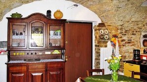A rustic kitchen with wooden cabinets, a tiled backsplash, and a stone wall.