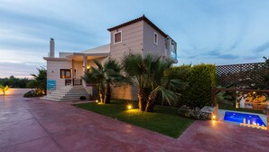 A two-story house with a swimming pool, a covered patio, and a well-maintained lawn. - Dimitrios Villa, a Luxury Oasis with Pool & Gym (Rethymno)