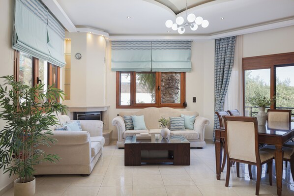 A spacious living room with a sofa set, a coffee table, and a dining area with chairs.