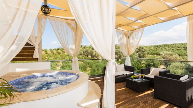 A hot tub on a wooden deck with outdoor seating and a view of greenery. - Dimitrios Villa, a Luxury Oasis with Pool & Gym (Rethymno)