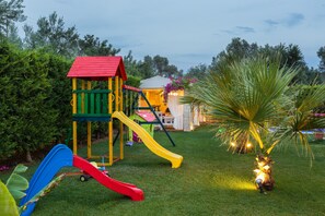 Une aire de jeux avec des toboggans et une petite structure en forme de maison.