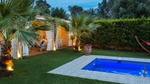 A backyard with a swimming pool, palm trees, and a patio area with chairs and a table. - Dimitrios Villa, a Luxury Oasis with Pool & Gym (Rethymno)
