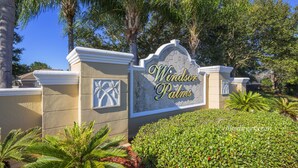 A sign for Windsor Palms with a stone wall and palm trees. - Treasure Hunt by VillaDirect (Kissimmee)