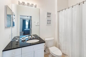 A bathroom with a black countertop sink, a white toilet, and a shower curtain. - Treasure Hunt by VillaDirect (Kissimmee)