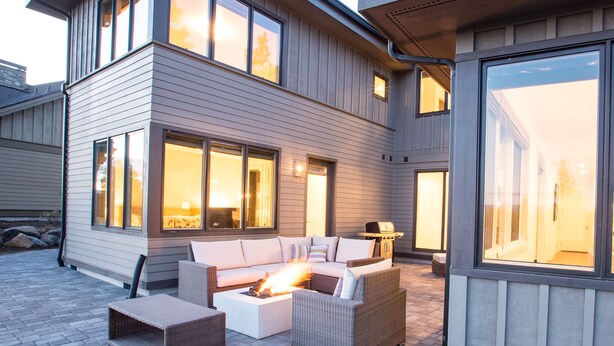 Une maison moderne dotée d’un patio aménagé avec un ensemble de canapés et un foyer extérieur.