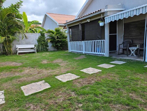 Ein Haus mit einer Veranda, einer weißen Bank und einem Kiesweg, der zum Eingang führt.