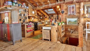 Interior rústico de una cabaña con paredes de madera, una zona de cocina y un comedor.