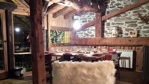 Interior rústico de madera con pared de piedra, techo de madera y un sillón cubierto de piel.