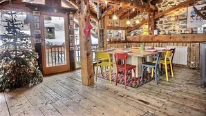 Un interior rústico de madera con una zona de comedor, un árbol de Navidad y paredes de piedra.