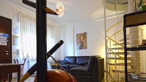 En stue med sofa, sofabord og en spiraltrappe.
