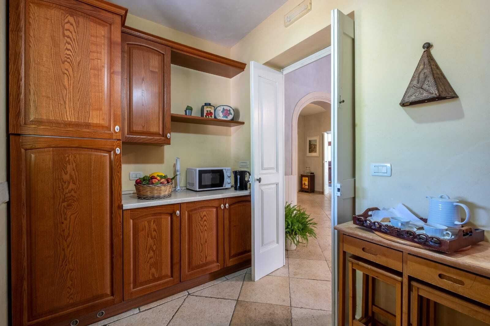 A kitchen with wooden cabinets, a microwave, and a tray with cups and a teapot.