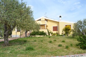 A yellow building with a sloped roof, a chimney, and a small balcony.