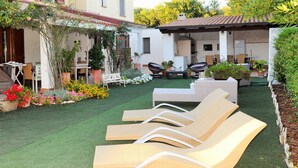 Une terrasse avec des meubles d’extérieur, une petite table et des plantes en pot.