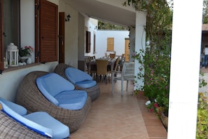 A covered patio with wicker furniture and a dining area.
