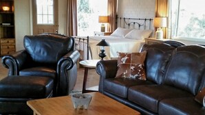 A cozy living room with a wooden ceiling, a black leather sofa, a wooden coffee table, and a patterned rug. - Foothills Ranch House in Casas Adobes, 8 ac estate with Pool, Tennis, Pickleball (Tucson)