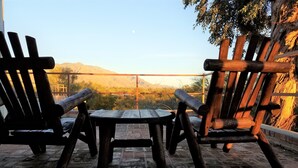 A patio with two wooden Adirondack chairs and a small table, overlooking a mountainous landscape. - Foothills Ranch House in Casas Adobes, 8 ac estate with Pool, Tennis, Pickleball (Tucson)
