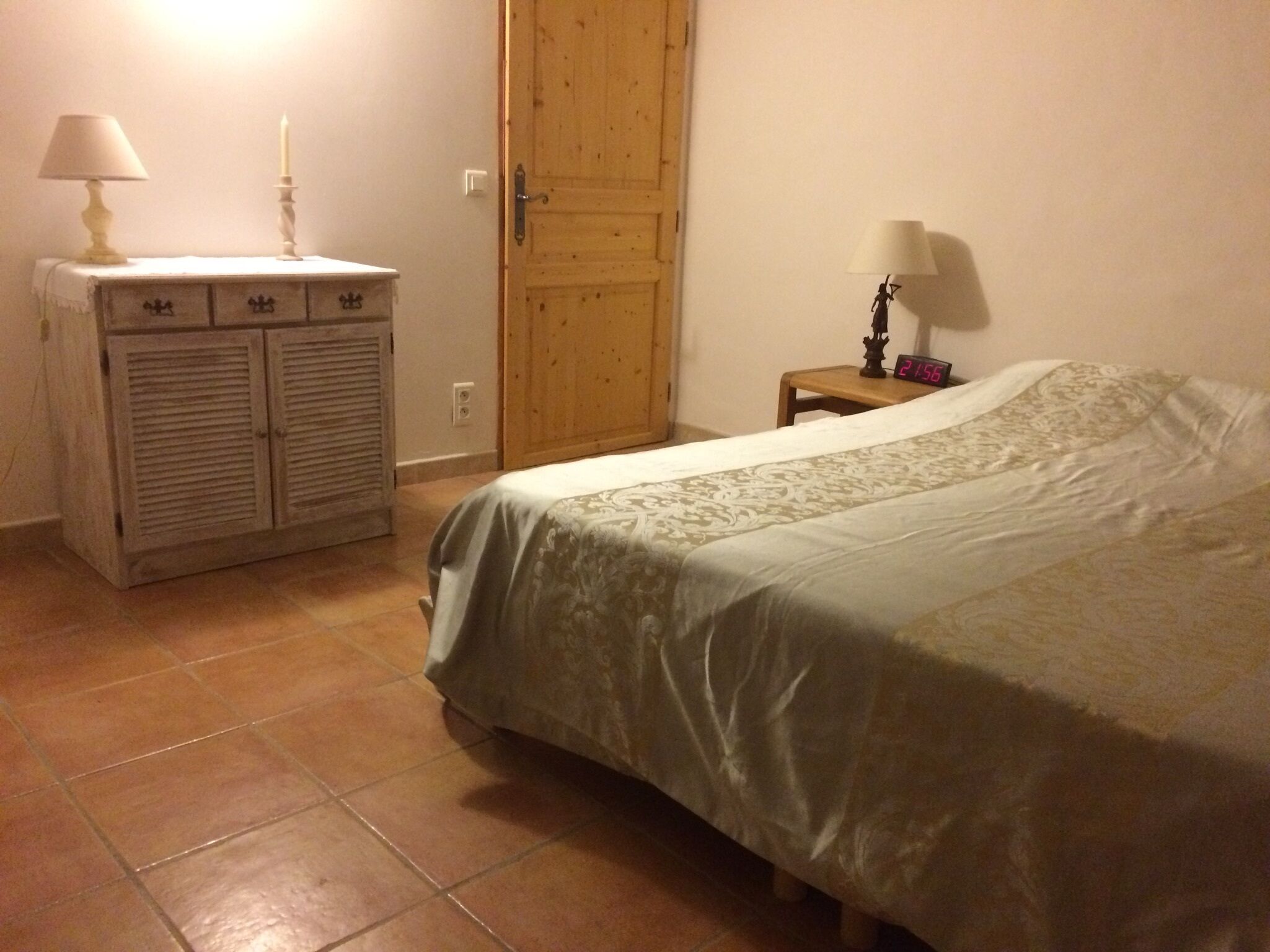 A bedroom with a bed, a dresser, a nightstand, and a wooden door.