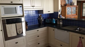Une cuisine avec des meubles blancs, un plan de travail bleu carrelé, un four à micro-ondes, un grille-pain et un évier.