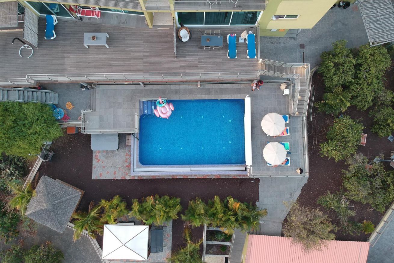 An aerial view of a swimming pool area with lounge chairs, a hot tub, and a small inflatable pool.