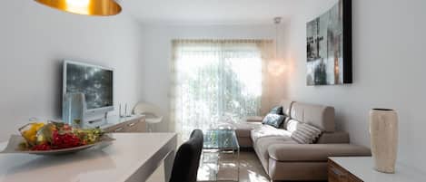 En moderne stue med sofa, spisebord og fjernsyn.