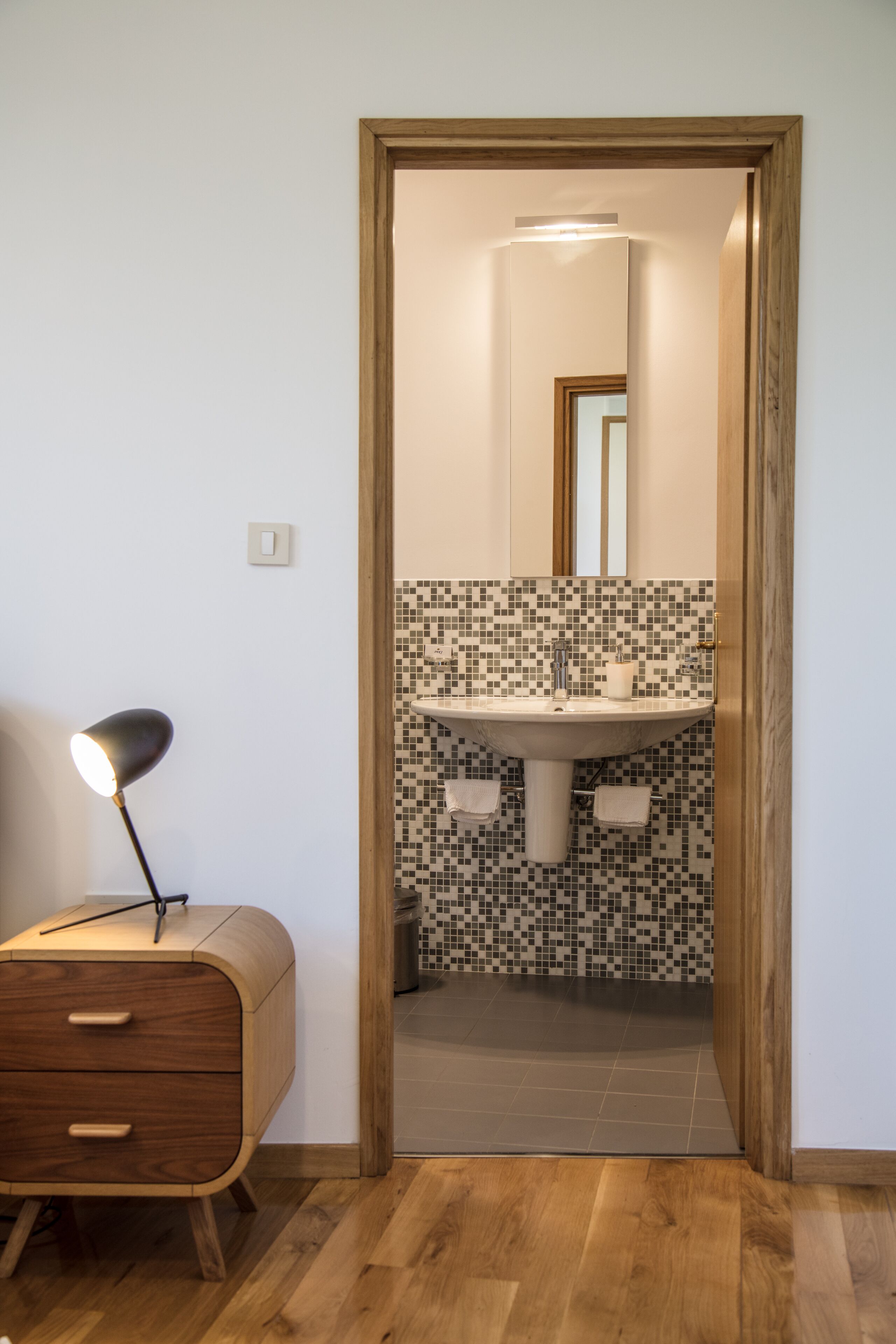 Ein Badezimmer mit Mosaikfliesen an der Rückwand, einem Waschbecken und einem Spiegel.