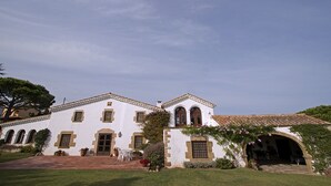 Um edifício branco com telhado em telhas, janelas em arco e uma porta central.