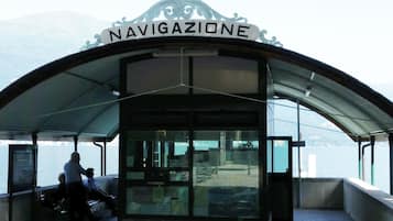 A covered area with a sign reading "NAVIGAZIONE" and a view of the water and mountains in the background.
