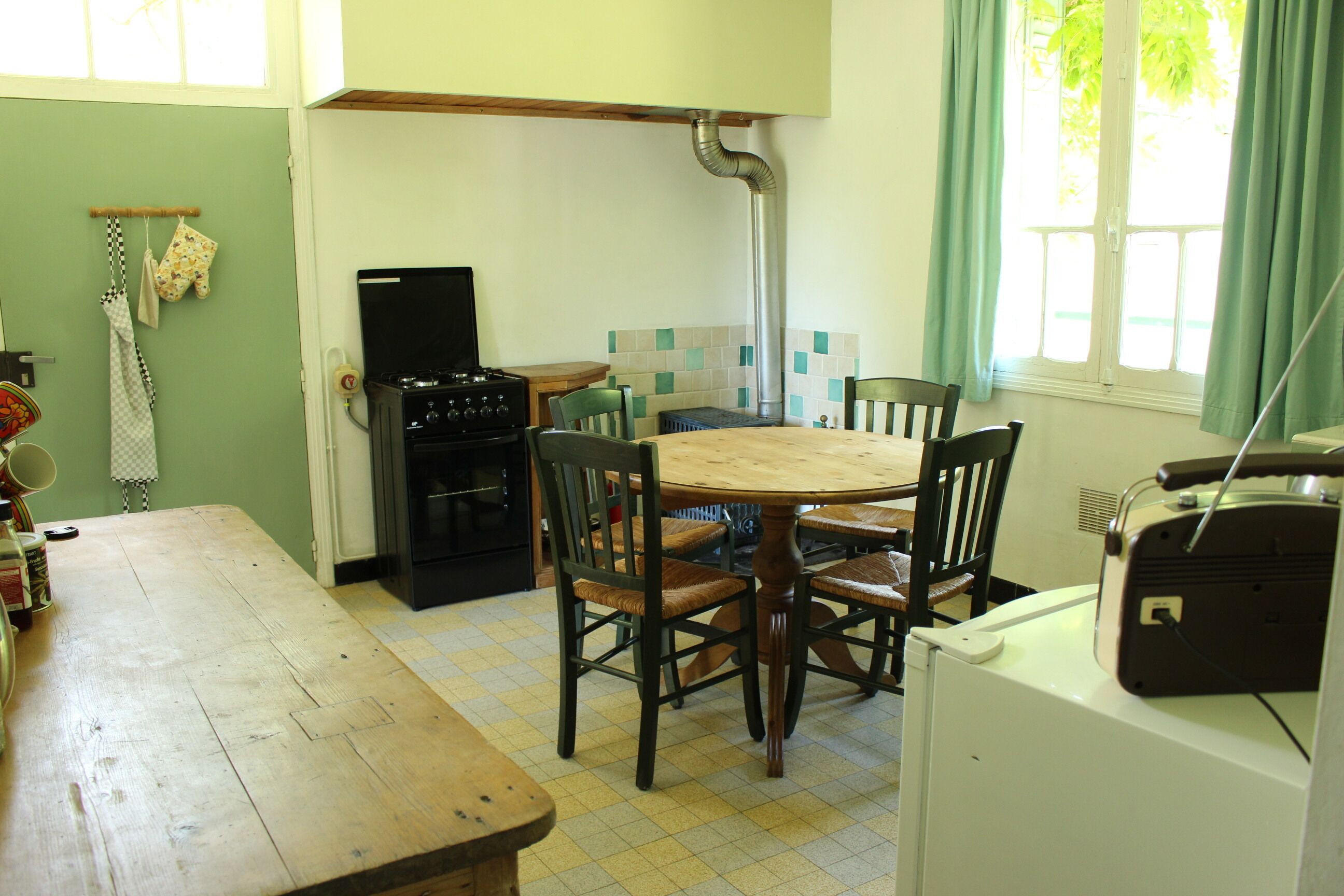 Een keuken met een houten tafel en stoelen, een fornuis en een koelkast.
