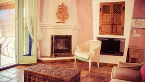 A living room with a fireplace, a television, and a wooden cabinet. - La Joya de Cabo de Gata - Cortijo El Cala Plomo (Agua Amarga)