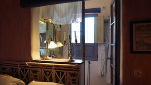 A room with a bed, a bedside table with a lamp, a mirror, and a window with curtains. - La Joya de Cabo de Gata - Cortijo El Cala Plomo (Agua Amarga)