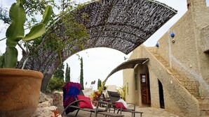 An outdoor seating area with stone flooring, a large potted plant, and a covered structure. - La Joya de Cabo de Gata - Cortijo El Cala Plomo (Agua Amarga)