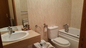 Een bad/douchecombinatie, handdoeken, zeep, toiletpapier