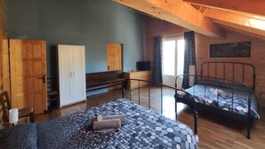 A room with two beds, a wooden wardrobe, a bench, and a television. - apt w3  in wood house first level (SAN BENEDETTO VAL DI SAMBRO)