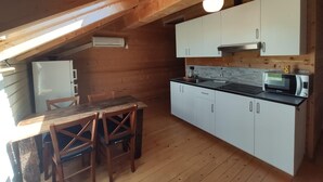 A compact kitchen with white cabinets, a microwave, and a refrigerator. There is a wooden dining table with chairs. - apt w3  in wood house first level (SAN BENEDETTO VAL DI SAMBRO)