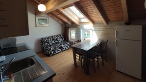A cozy kitchen with wooden beams, a dining table, and a refrigerator. - apt w3  in wood house first level (SAN BENEDETTO VAL DI SAMBRO)