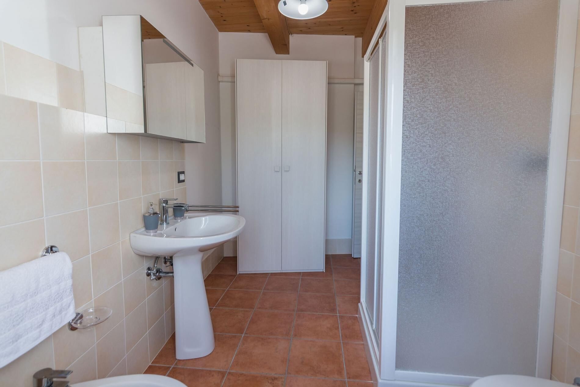 Een badkamer met een wastafel op een voetstuk, een toilet en een douchehoek.