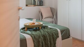A neatly made bed with a green blanket, a tray with breakfast items, and a chair in the background. - Villa Rosa - Private villa, 5 bedrooms, pool, A/C, wifi, pets, Marche (Fossombrone)