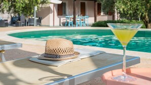 A poolside area with a lounge chair, a straw hat, and a martini glass. - Villa Rosa - Private villa, 5 bedrooms, pool, A/C, wifi, pets, Marche (Fossombrone)