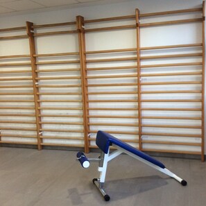 A room with a blue and white exercise bench against a wall with horizontal wooden slats.