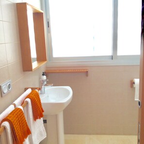 A bathroom with a white sink, a mirror, and a window.
