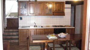 A kitchen with wooden cabinets, a sink, a stove, and a dining table with chairs.