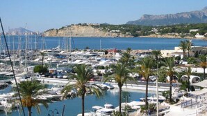 A marina with numerous boats docked, palm trees, and a mountainous backdrop. - Exclusive apartment, big terrasse 4 pools, close to restaurants beaches and golf (Benissa)