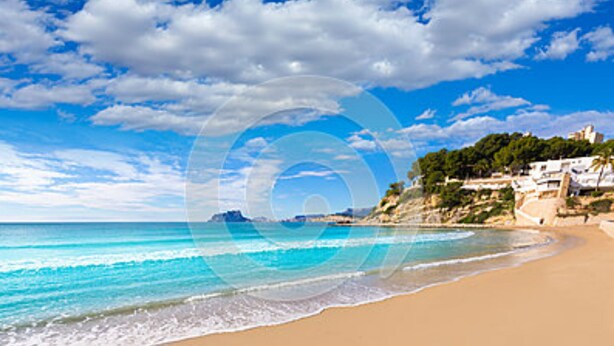 A beach with clear blue water, sandy shore, and buildings on a hillside. - Exclusive apartment, big terrasse 4 pools, close to restaurants beaches and golf (Benissa)