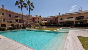 A swimming pool with a wooden deck, surrounded by buildings with balconies and a clear sky. - Exclusive apartment, big terrasse 4 pools, close to restaurants beaches and golf (Benissa)