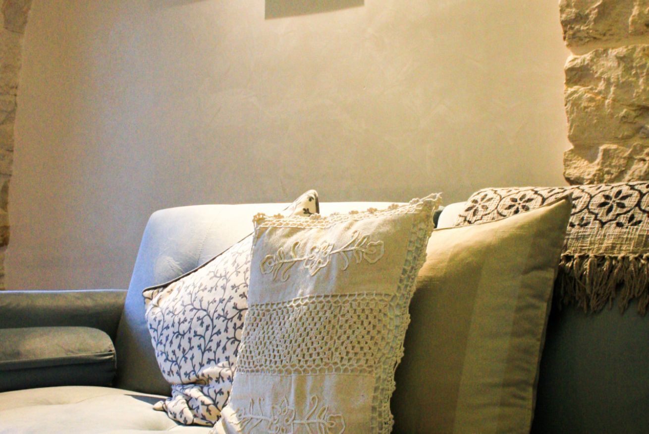 A beige sofa with patterned cushions and a textured throw blanket.