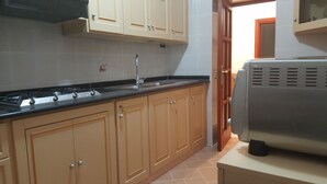 A kitchen with beige cabinets, a black countertop, a stainless steel range hood, and a built-in oven. - Apartment in the heart of Sorrento, 10 meters from Piazza Tasso (Sorrento)