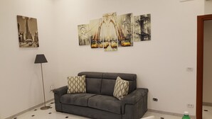 A living room with a grey sofa, patterned cushions, and a black floor lamp. - Apartment in the heart of Sorrento, 10 meters from Piazza Tasso (Sorrento)