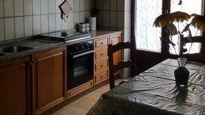 Una cucina con mobili in legno, un fornello e un tavolo da pranzo con un vaso.