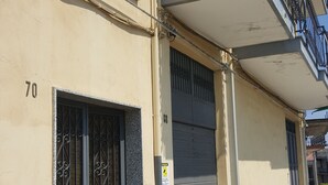 Un edificio con un portone garage chiuso, un cancello metallico con decorazioni a barre e un balcone con ringhiera in metallo.